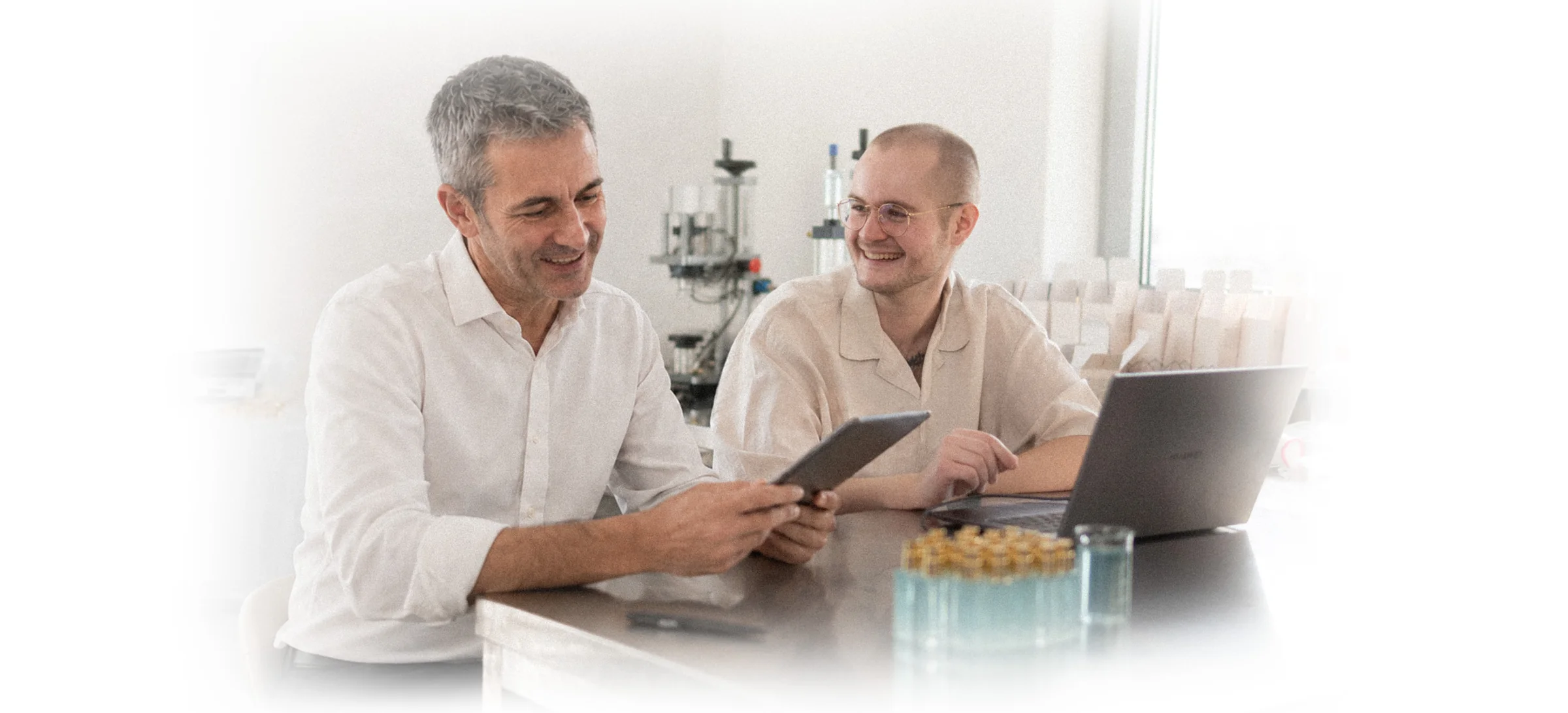 Benjamin Hille und ein Mitarbeiter arbeiten gemeinsam an Tablet und Laptop im Betrieb